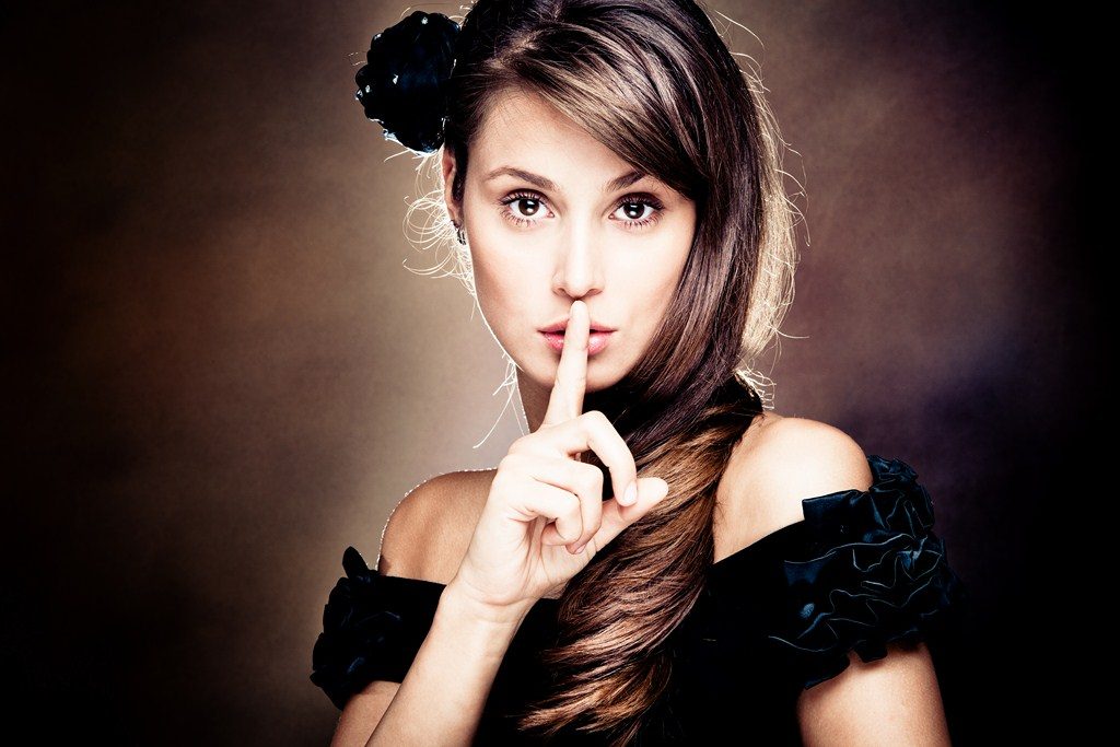 beautiful young woman gesturing silence, studio shot